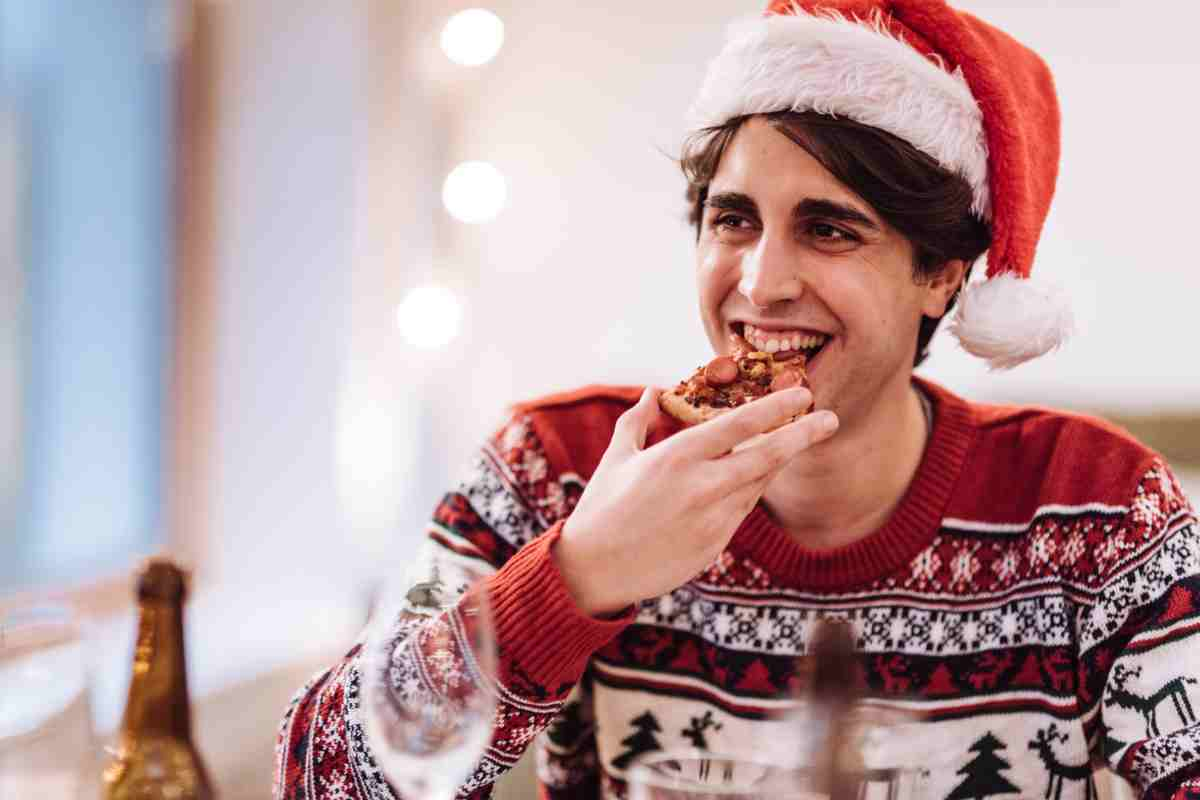 ragazzo con cappello di babbo natale mangia cercando di non ingrassare durante le feste